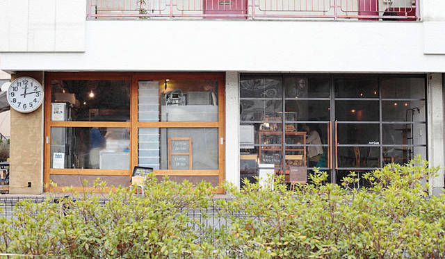 <b>AOSAN｜アオサン</b>　看板を掲げない店舗は、大きな丸時計と向かいの公園が目印。通りからは、ガラス張りの厨房でパンを焼くようすが見られる。店内には、小さなカフェスペースも。