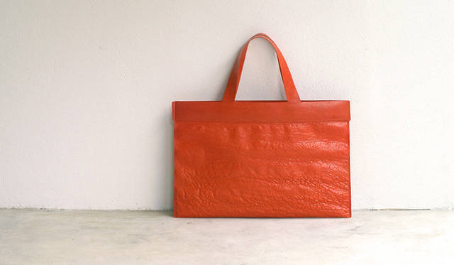 <strong>DESIGNTIDE TOKYO 2010｜TIDE Market</strong>　TIDE Market『PE A3BAG』/PE<br>クラフトデザイナー 佐藤延弘による「PE（ペ）」は、ゴミ袋やレジ袋として、日常でよく手にしているポリエチレン（プラスチック）を素材としたプロダクトシリーズ。薄さ0.02～0.04mmのフィルムを、電気コテで熱溶着しながら幾層にも重ね合わせていくことでつくられている。熱で融けた縮みや凹凸の表情、プラスチックの光沢感、クッション性のある軽くしなやかな質感が特徴。完成までの全行程は手仕事でおこなわれる。