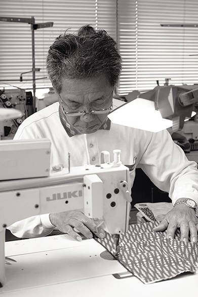 "NALUTO TRUNKS" is a surf trunk brand founded by Teruyoshi Yamaguchi, the second generation of the swimwear manufacturer "Yamaguchi Sewing" in Naruto City, Tokushima Prefecture. Pictured is his father, Michio Yamaguchi.