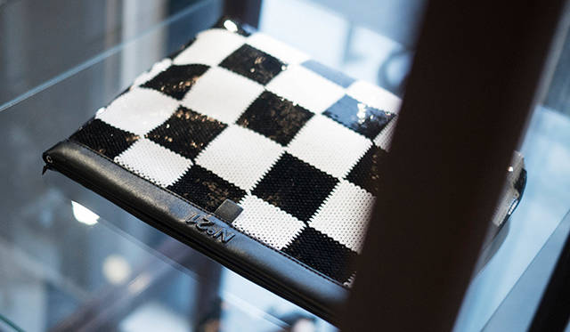A women's clutch bag featuring a checkerboard pattern rendered in sequins.