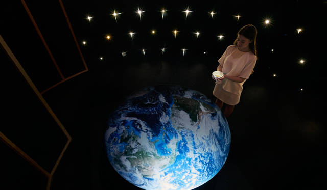 Zone 3, Scene 3, set in a dark room representing space, featured a circular table with an image of the Earth projected onto it.